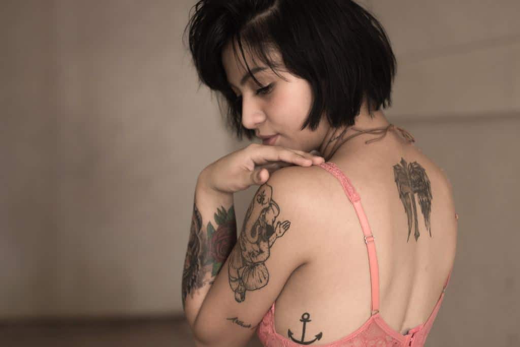 Dark haired woman in a pink bra looks over her shoulder