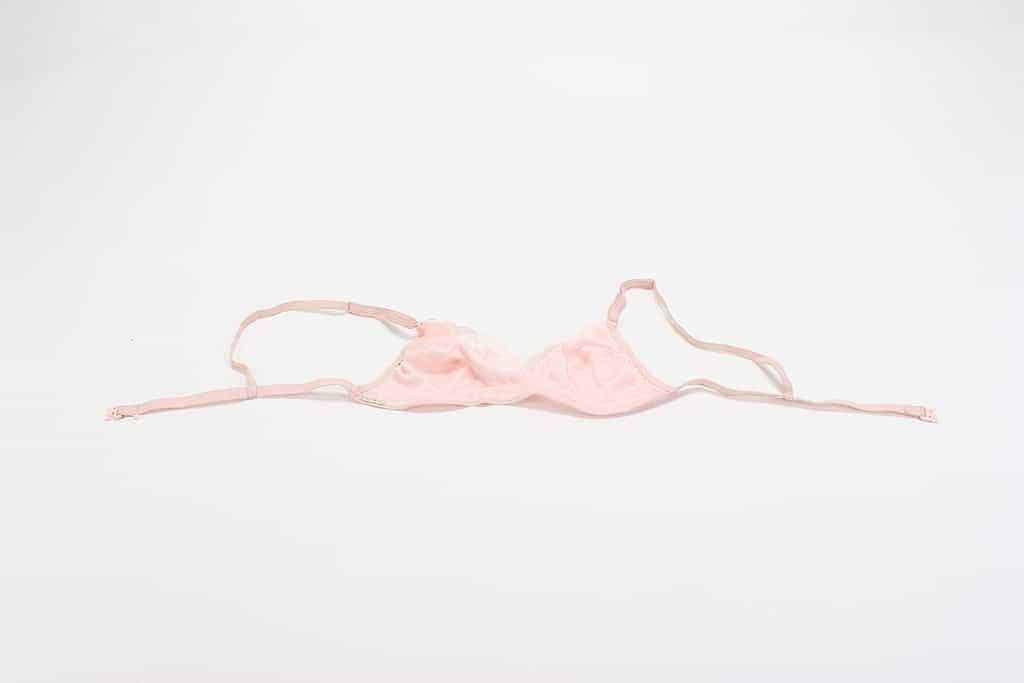 Pink lacey bra laid out on a white background