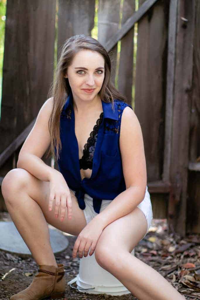 Blue sleeveless button down with black bralette and white shorts