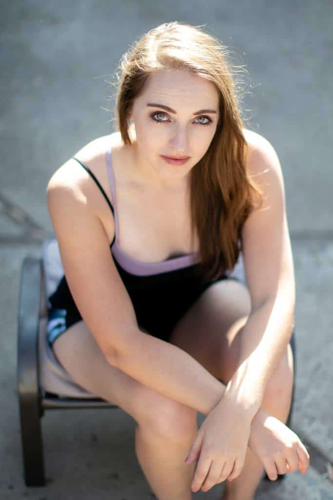 Woman wearing purple strappy back bralette with black spaghetti strap tank and workout shorts