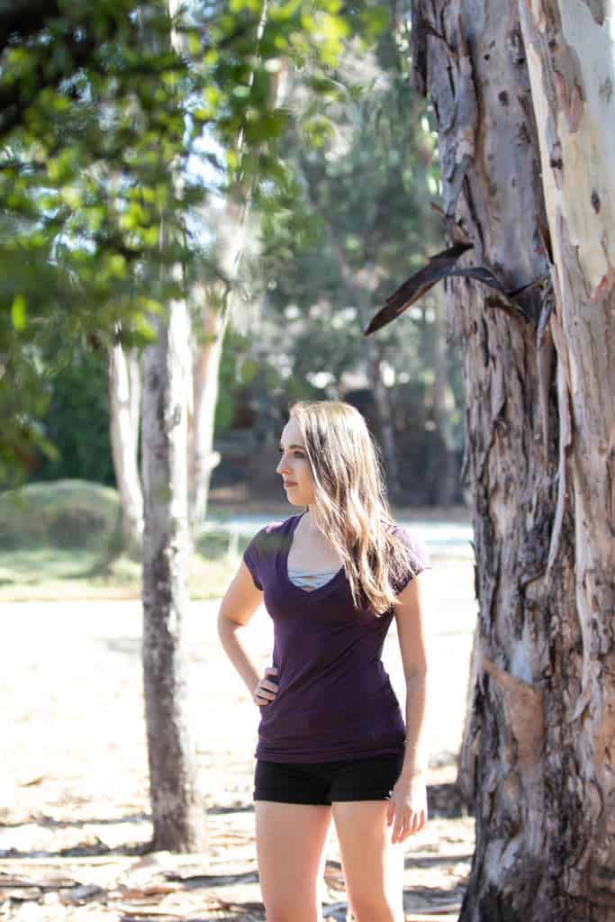 Woman wearing a plum shirt with a gray bralette underneath