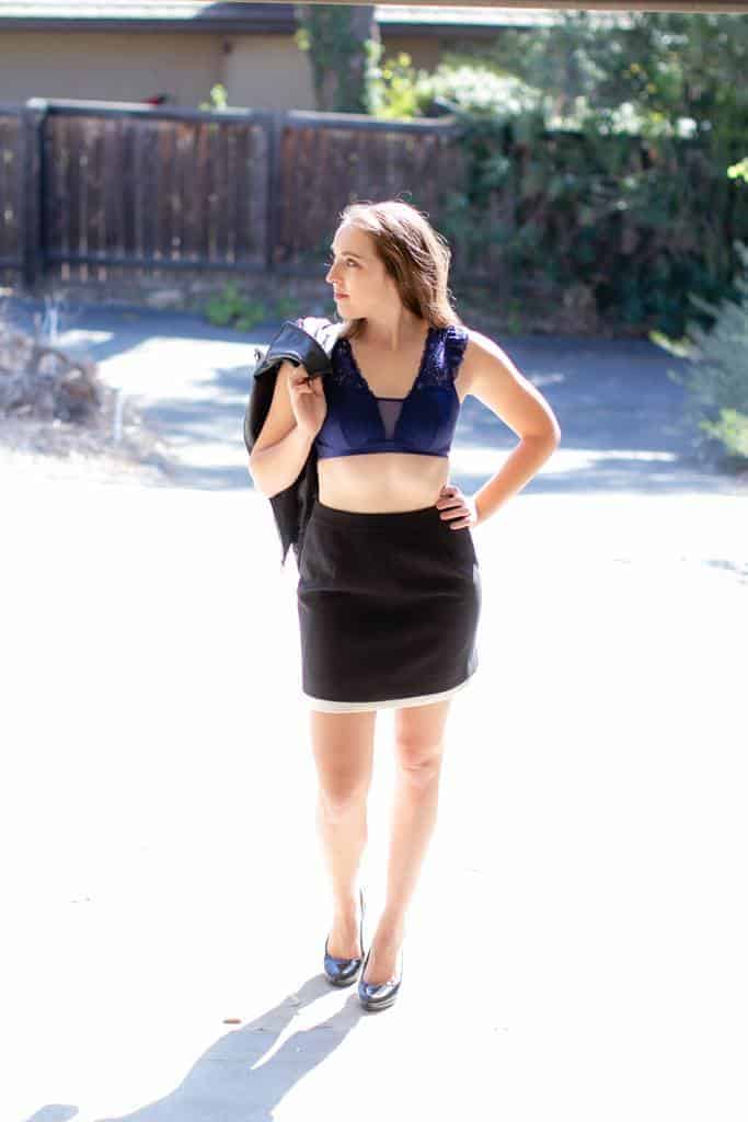 Woman wearing a blue lace bralette with black skirt and leather jacket on her way to work