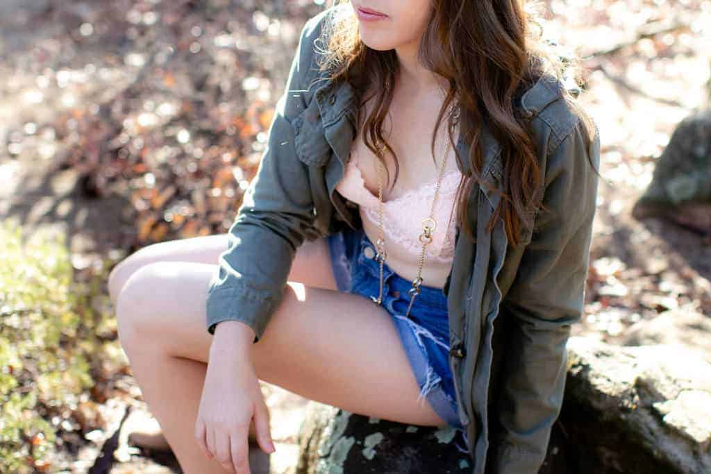 Woman wearing pink bralette with green anorak, denim shorts and boots