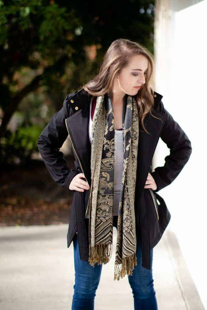 Woman wearing a bralette under white tank, jacket, and scarf for work