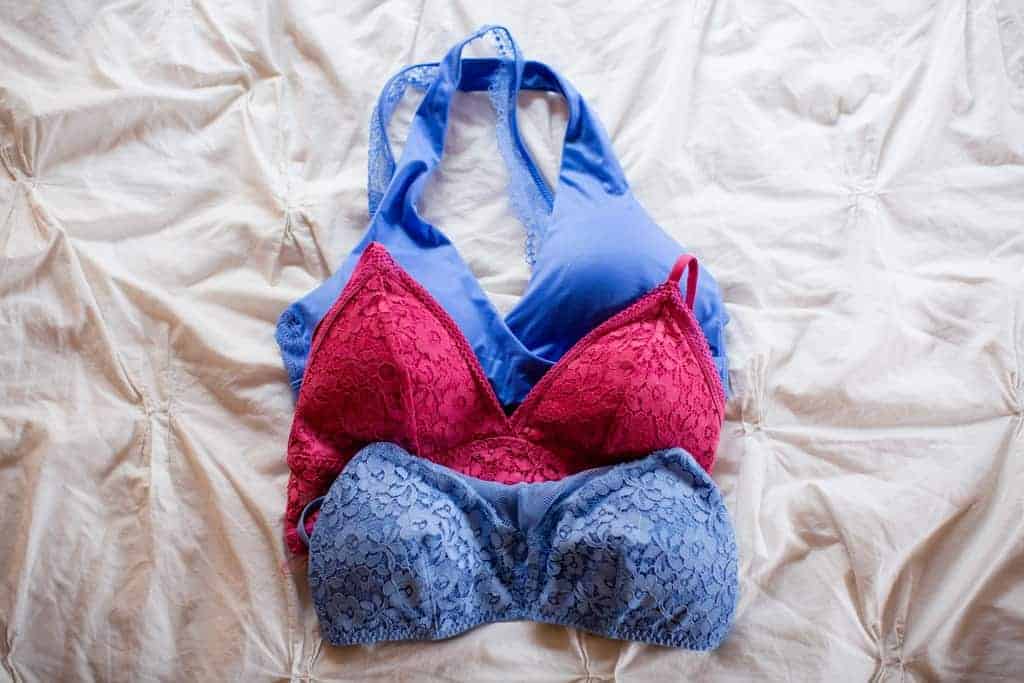 Close up of three layered bralettes on a bed