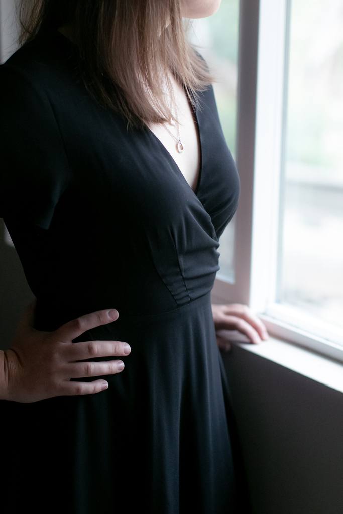 Woman by a window wearing a black deep v dress