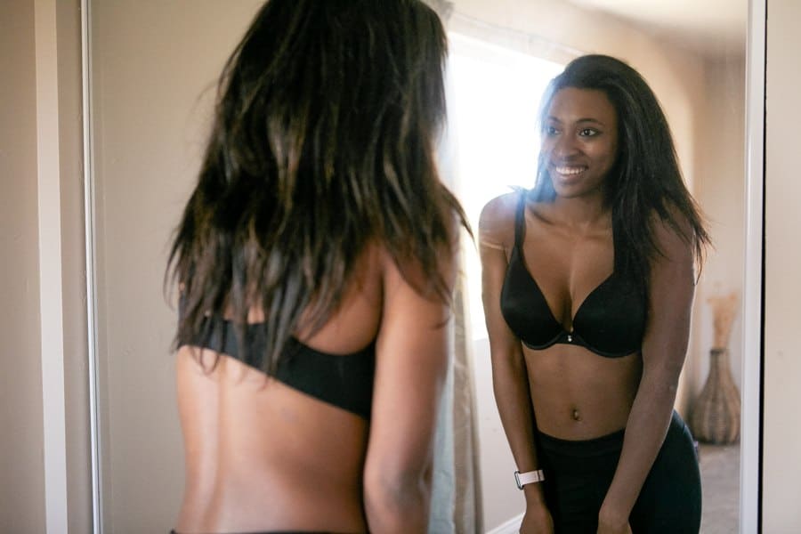 Woman looking at her reflection in the mirror while wearing a black bra