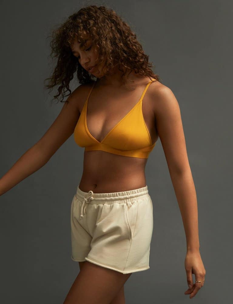 Woman wearing an orange bralette with white shorts