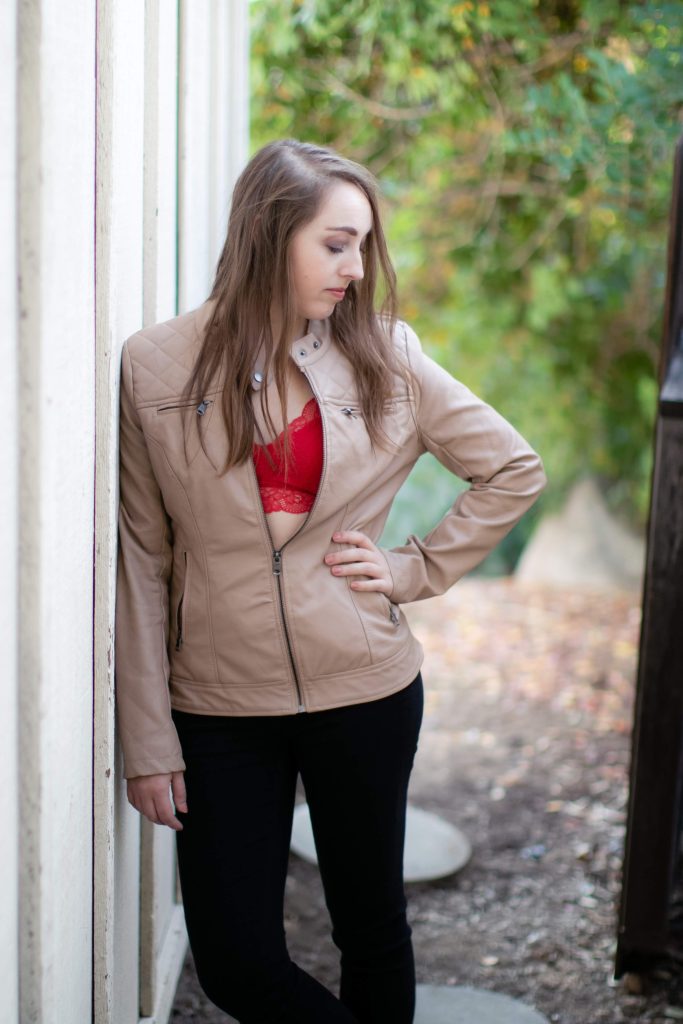 Woman wearing a red bralette and brown jacket