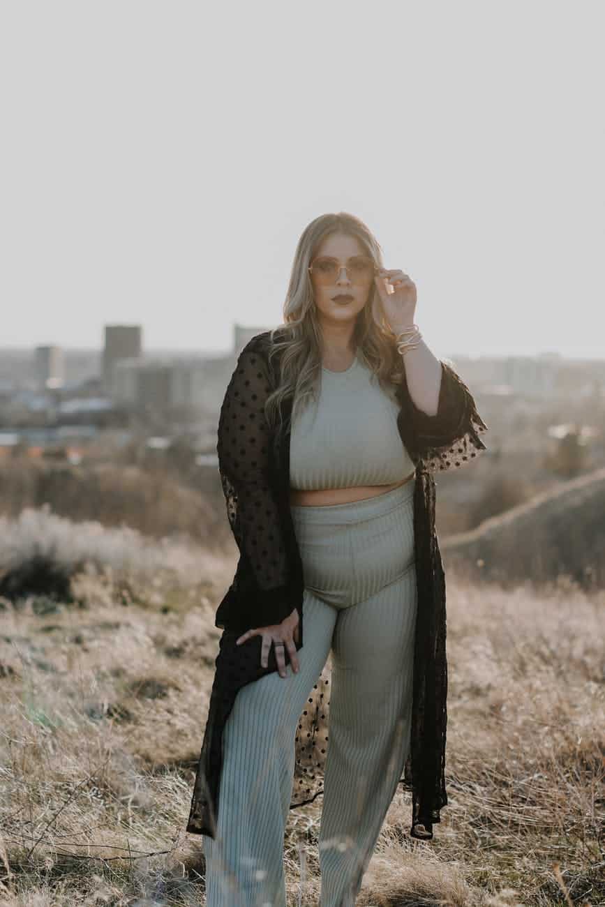 Woman wearing a long cover up for her crop top and pant suit set