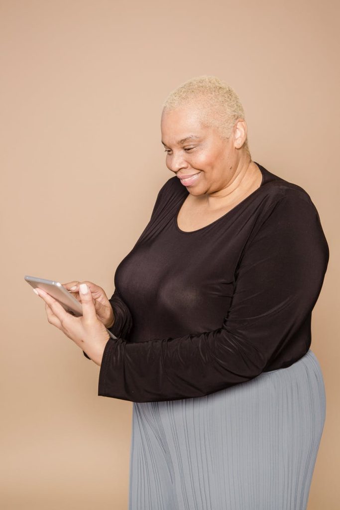 Woman using her phone while wearing a black top and gray pants