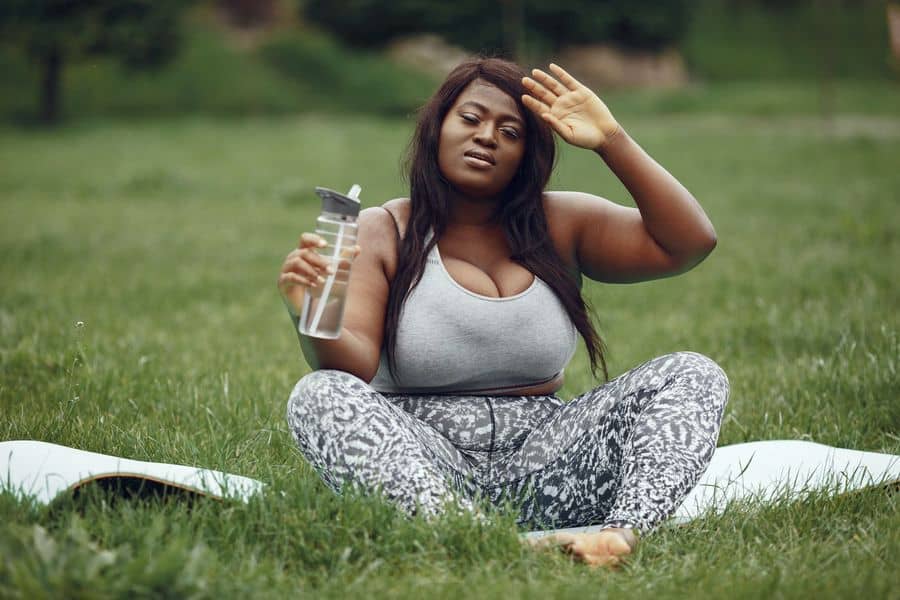 Woman wearing a gray sports bra while drinking from her water bottle