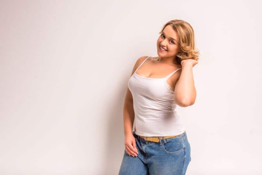 Woman wearing a white spaghetti strap top and jeans