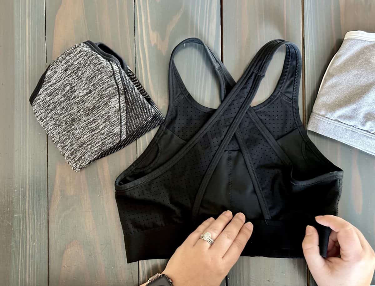 Woman folding 3 padded and unpadded sports bras on a wooden table