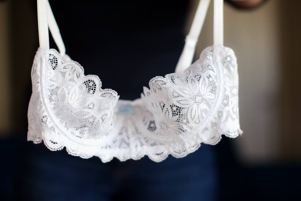 A close-up image of a white laced bra