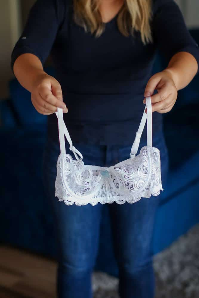 A girl wearing a dark blue shirt holding a white laced bra