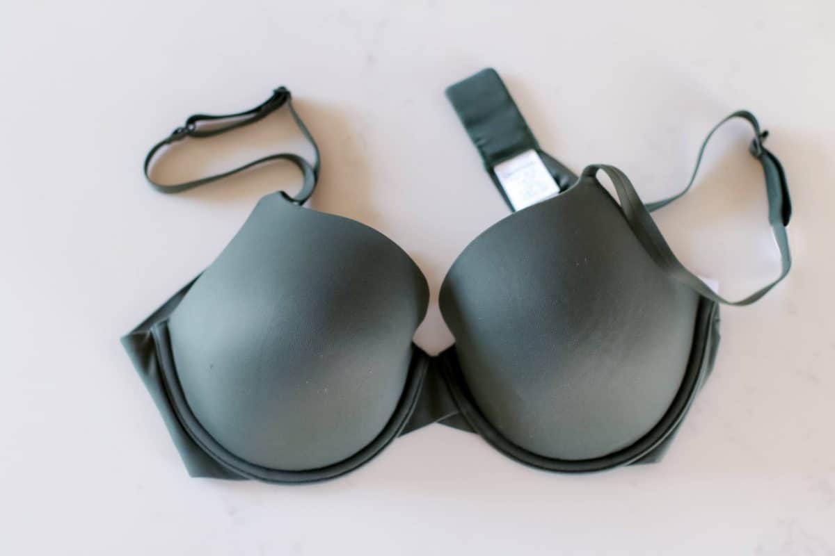 A top view of a gray full-coverage bra placed on a white surface
