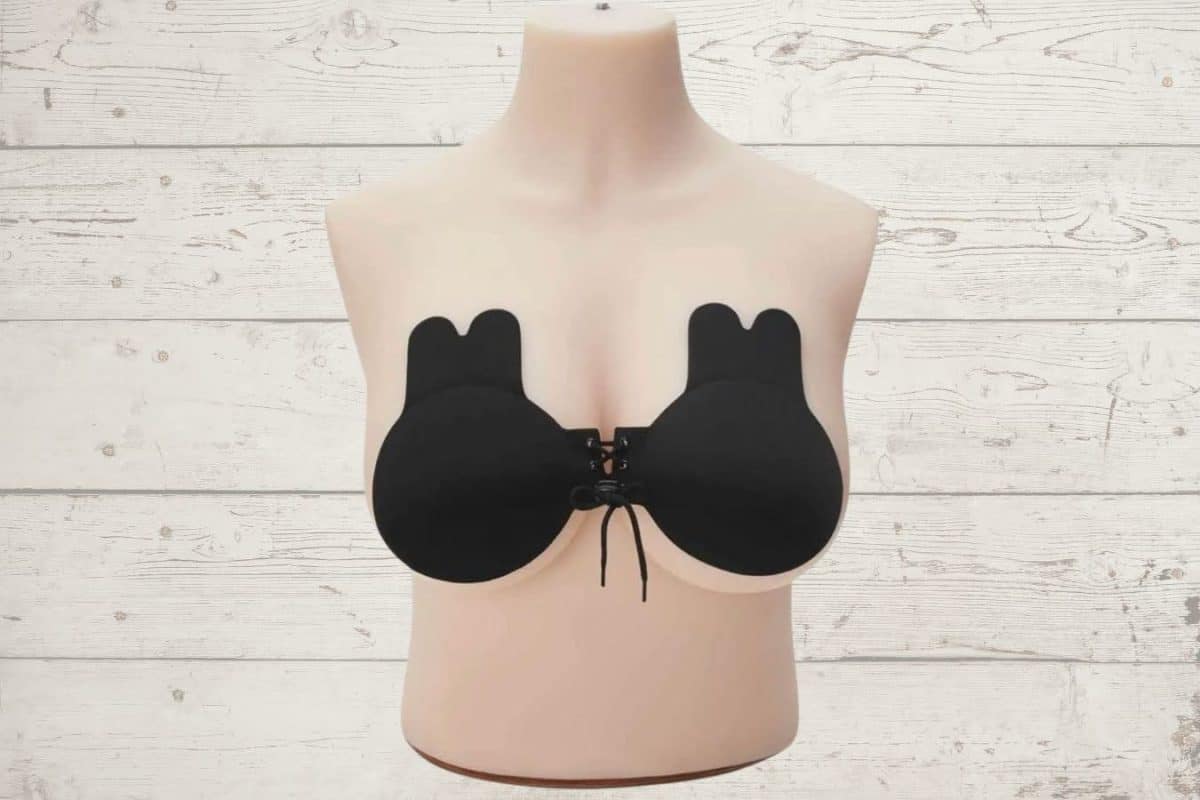A pull-together black sticky bra is stuck on a brown mannequin placed on a wooden background