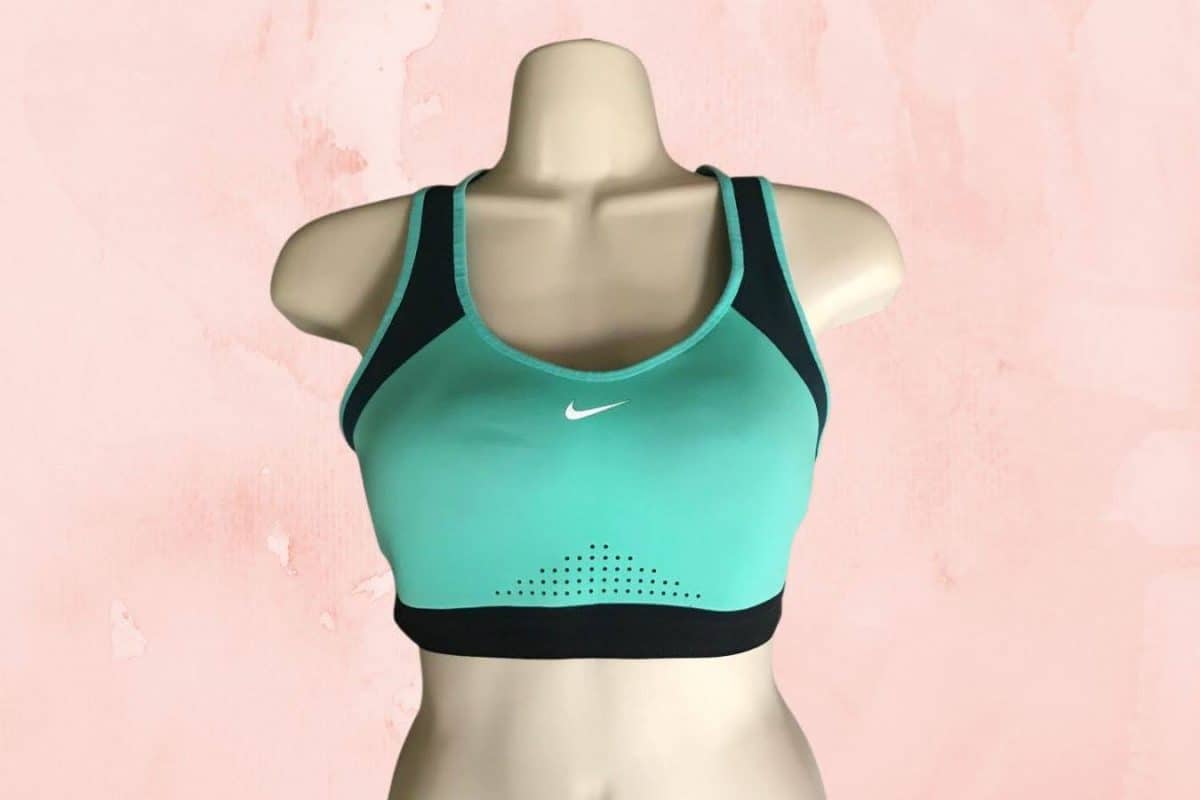 A green Nike sports bra placed on a white mannequin with pink background