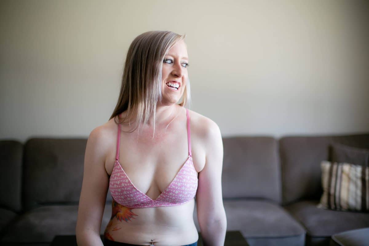 A woman in a pink wireless bra with thin straps is seated on a black table
