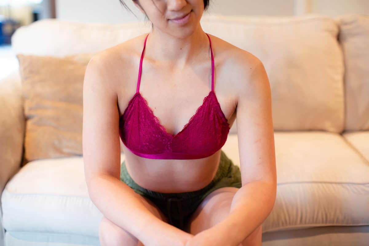 A pink bralette and green shorts are worn by a woman seated on a couch