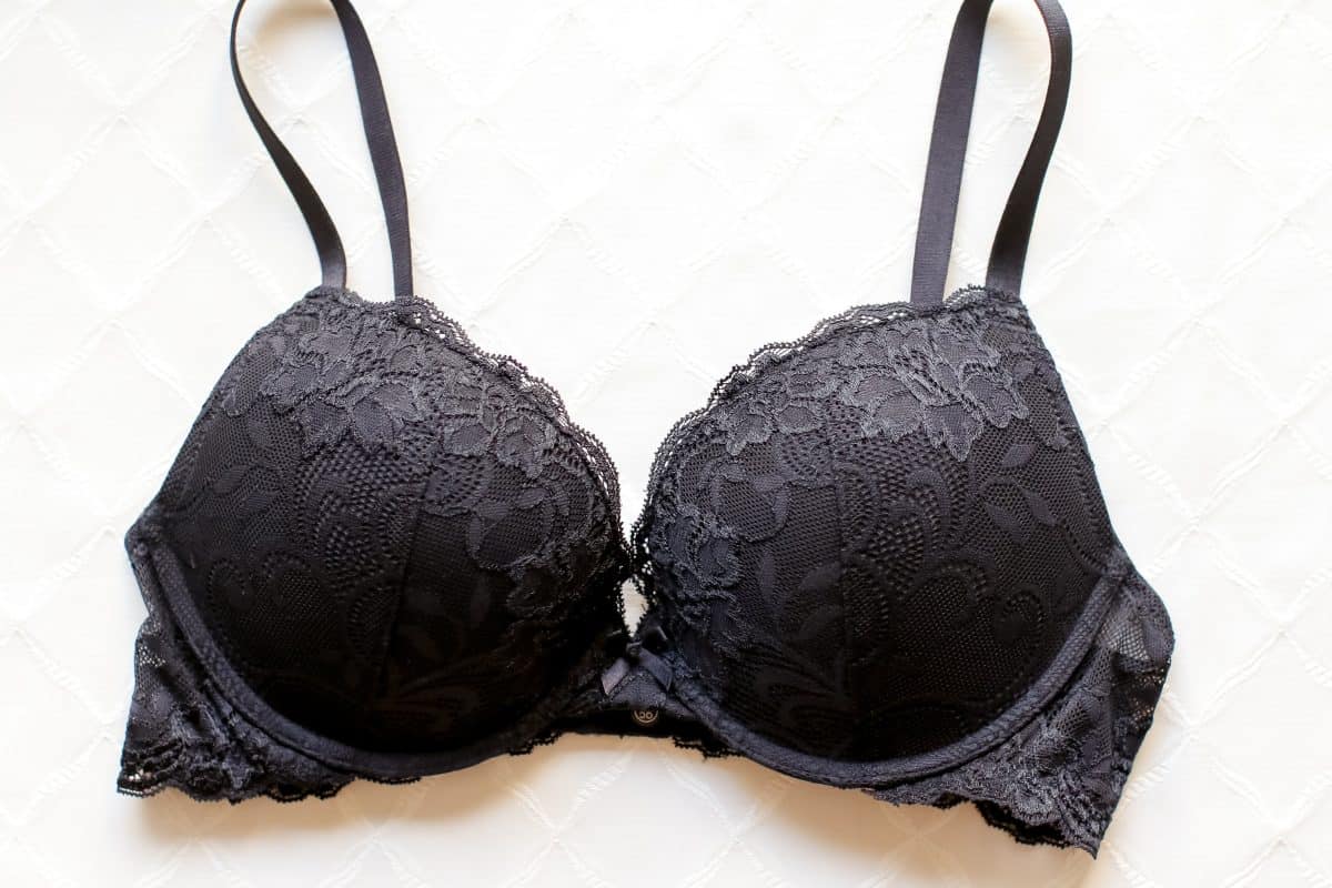 A black plunge underwire bra with a floral lace design and a ribbon at the center