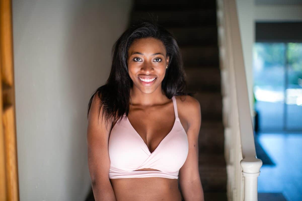 A woman wearing a white racerback full-coverage bra standing near a staircase