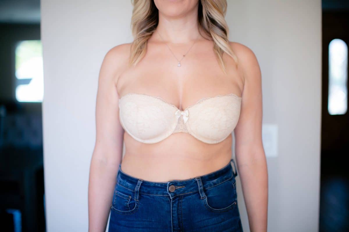 A white full-coverage strapless bra with underwire and denim shorts worn by a woman