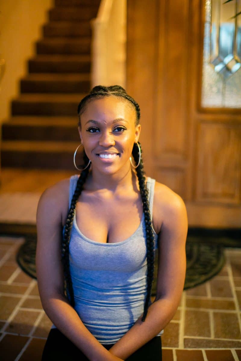 A gray tank top and black leggings are worn by a woman in a ponytail