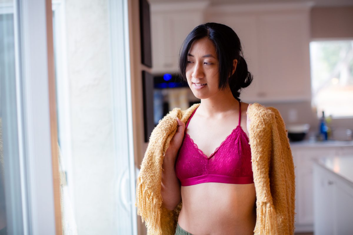 A woman wearing a pink bralette with a yellow shawl on her shoulder