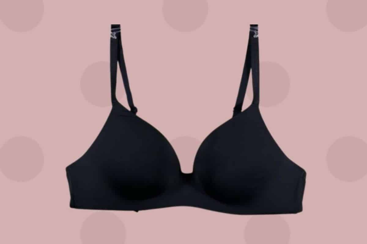 A black seamless bra with adjustable straps placed on a pink background