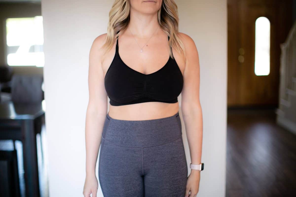 A black spaghetti straps sports bra and gray leggings are worn by a woman