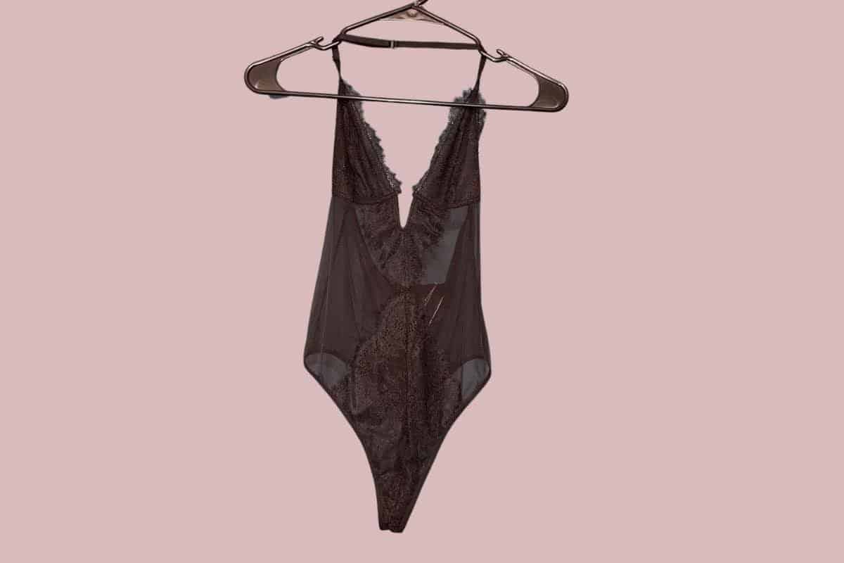 A black halter Teddy lingerie with a lace design hangs on a black hanger