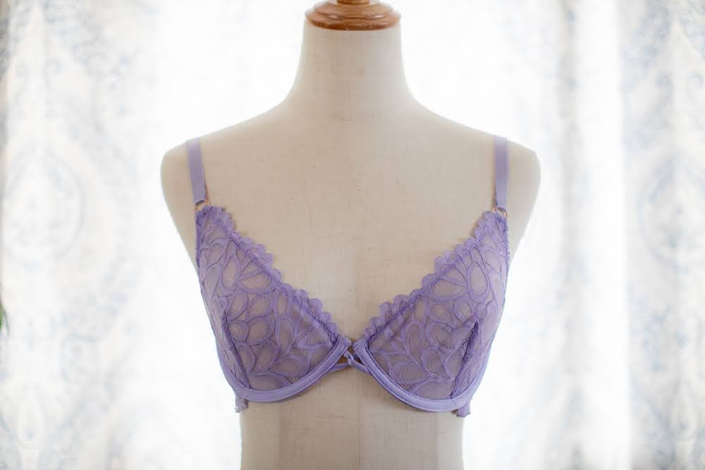 A purple underwired demi bra with lace placed on a white mannequin