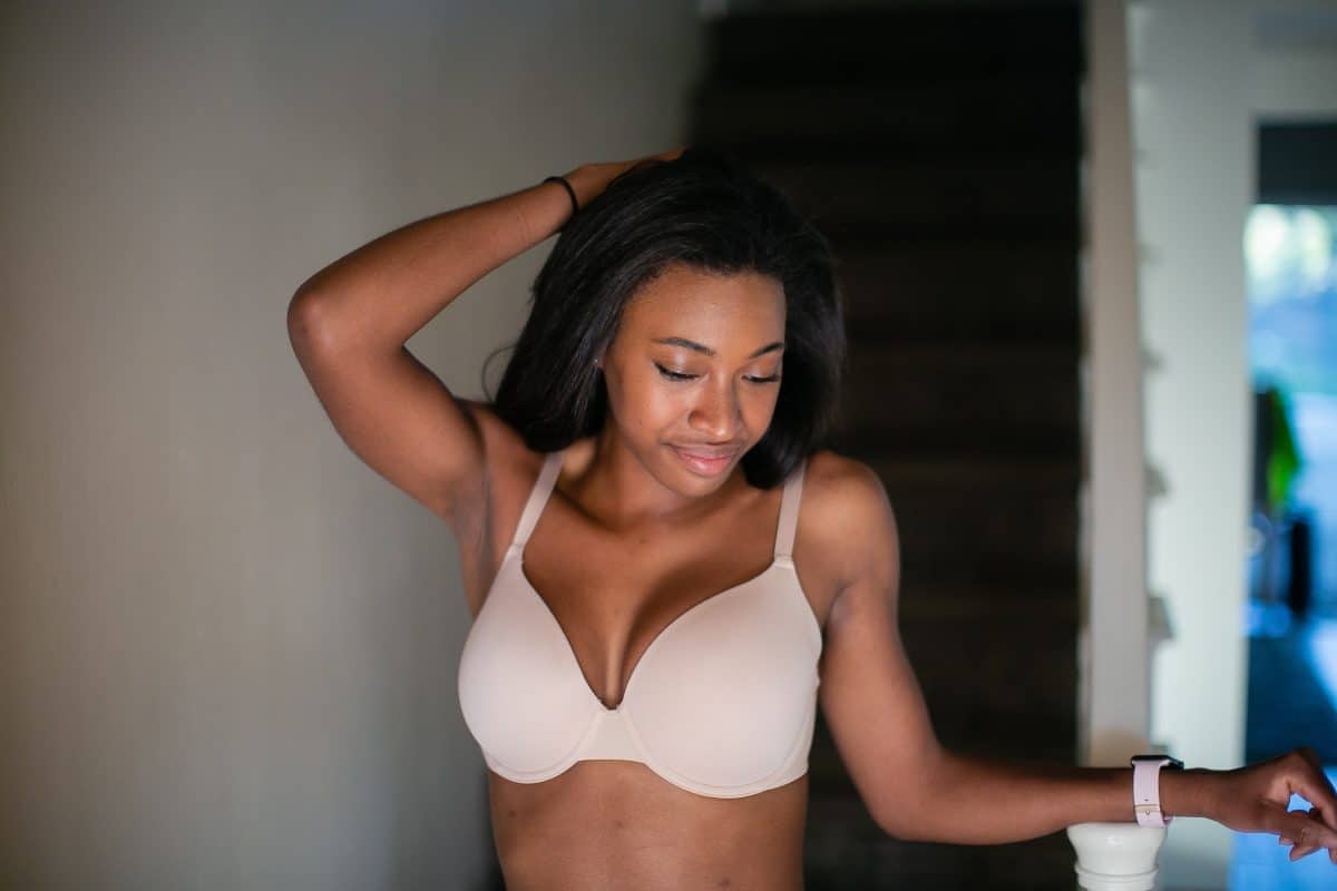 A woman wearing a white push-up bra with underwire and adjustable straps standing near a staircase