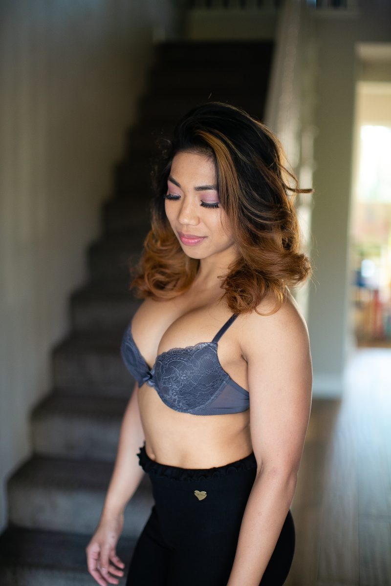 A gray push-up bra with underwire and black leggings worn by a woman standing near a staircase