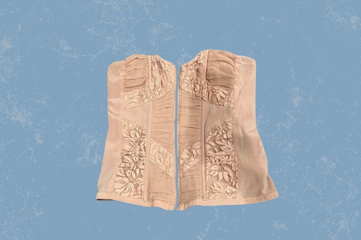 A cream corset with a lace floral design placed on a blue background
