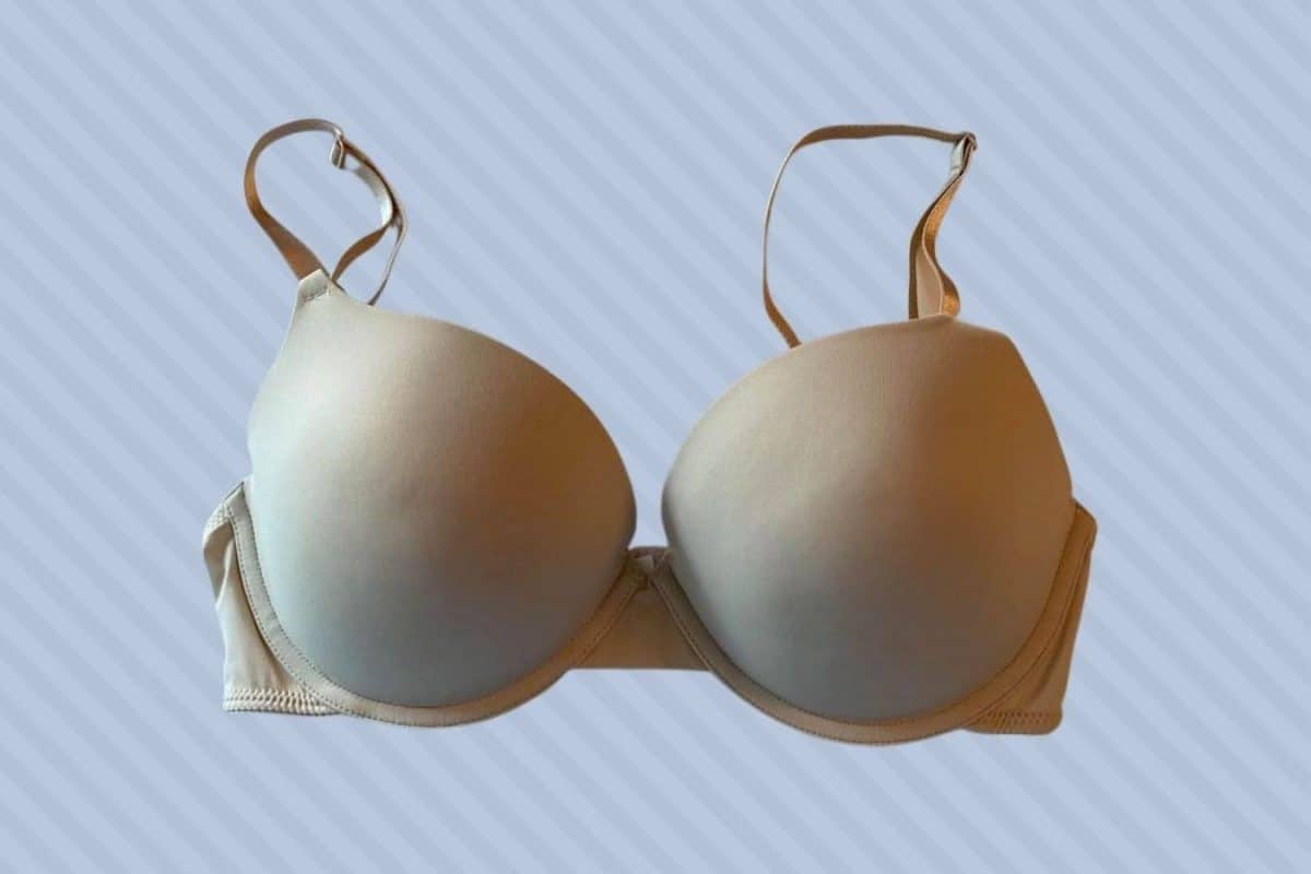 Nude push-up bra with underwire and adjustable strap placed on a blue background