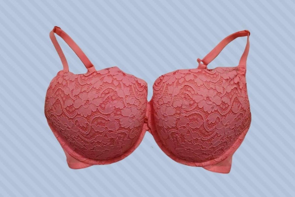 Peach underwired push-up bra with lace flower design and adjustable strap placed on a blue background