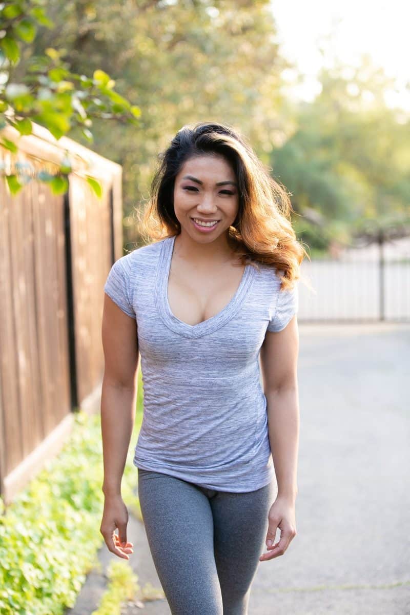 A woman wearing a gray t-shirt and gray leggings walking on the street