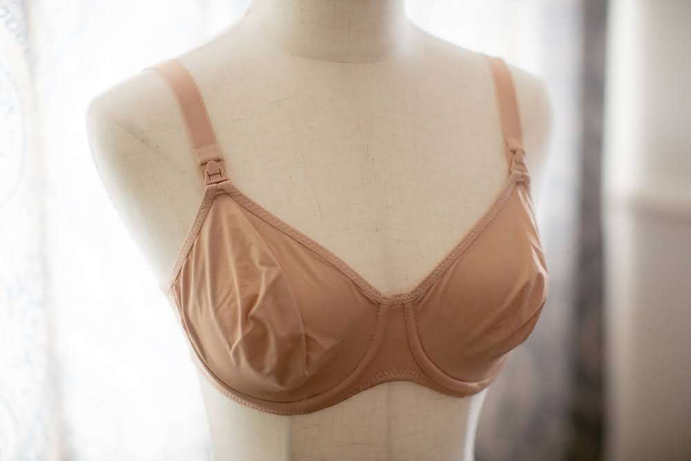 A brown nursing underwired bra with front clips placed on a white mannequin