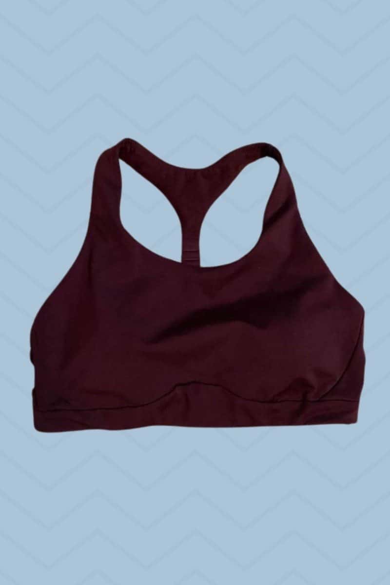 A maroon racerback seamless sports bra placed on a blue background