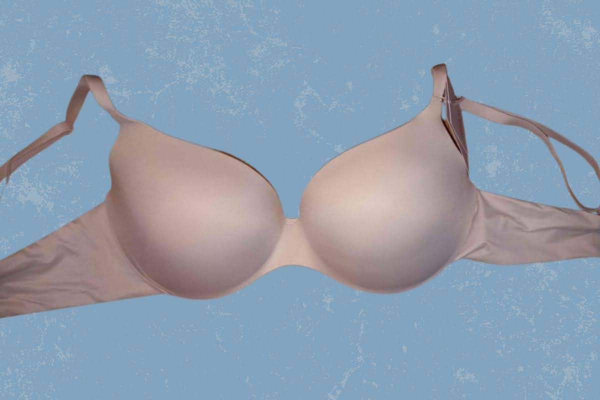 A light pink full-coverage wireless bra with a tag placed on a blue background