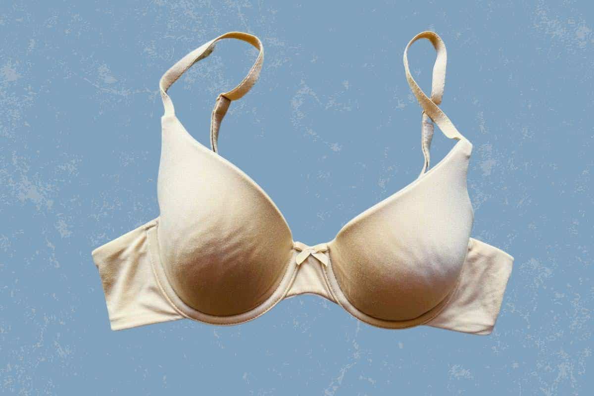 A nude push-up underwired bra with adjustable straps and ribbon at the center is placed on blue background