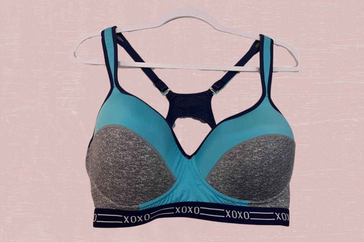 Tri-colored sports bra with underwire hangs on white hanger placed on pink background