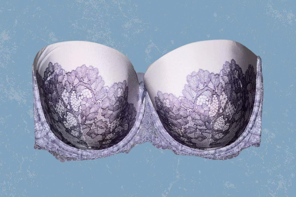 A white full-coverage strapless bra with underwire and purple lace design placed on a blue background