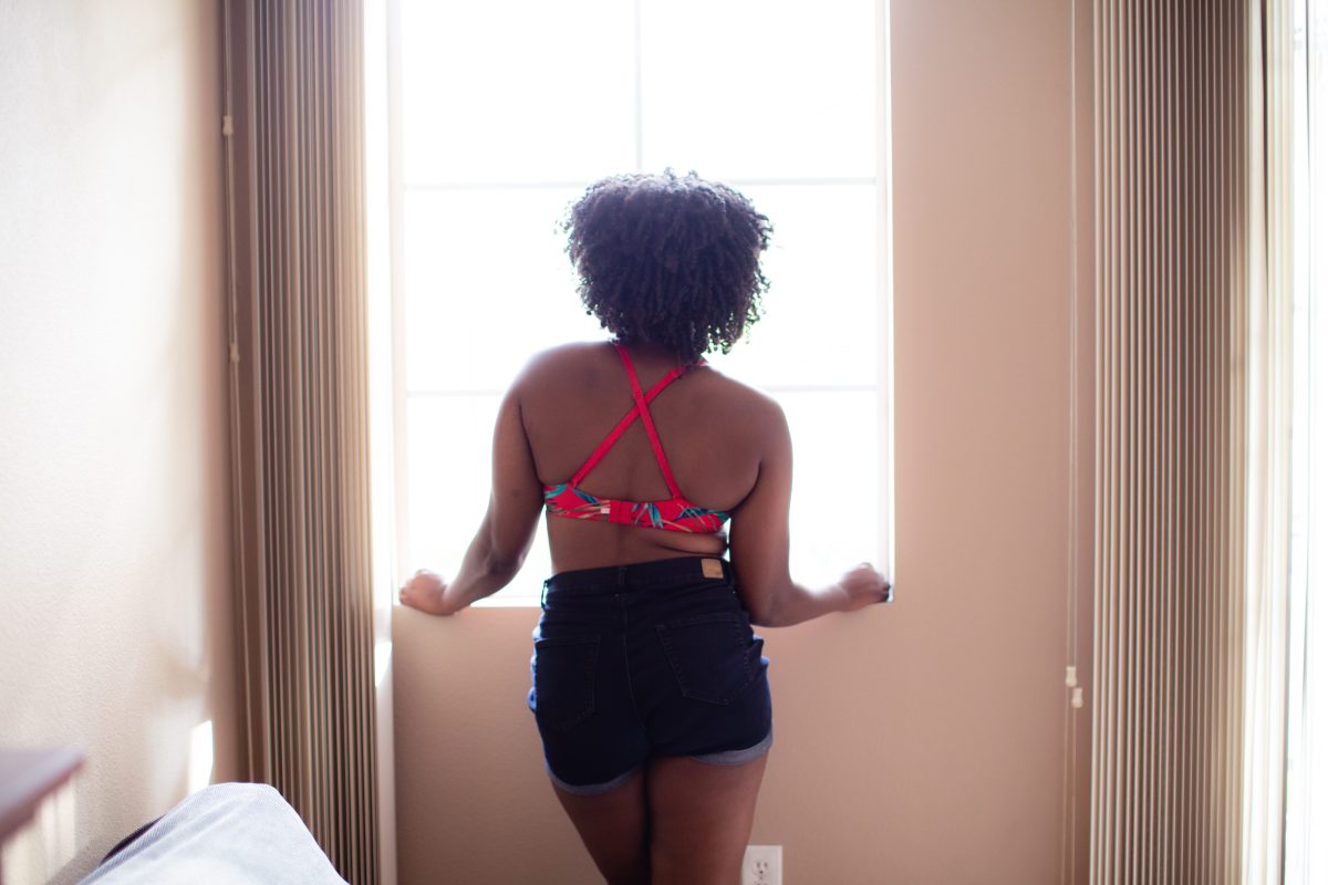 A back view of a woman in a red bra with a summer design and wearing denim shorts