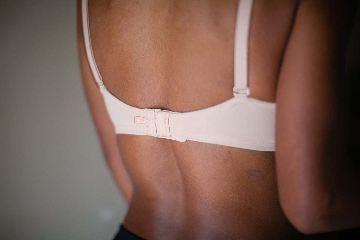 A back view of a white bra with adjustable straps and bra hooks worn by a woman