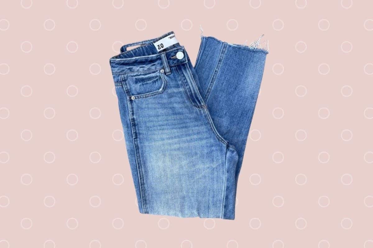 Straight cut high-waisted denim jeans placed on a pink background