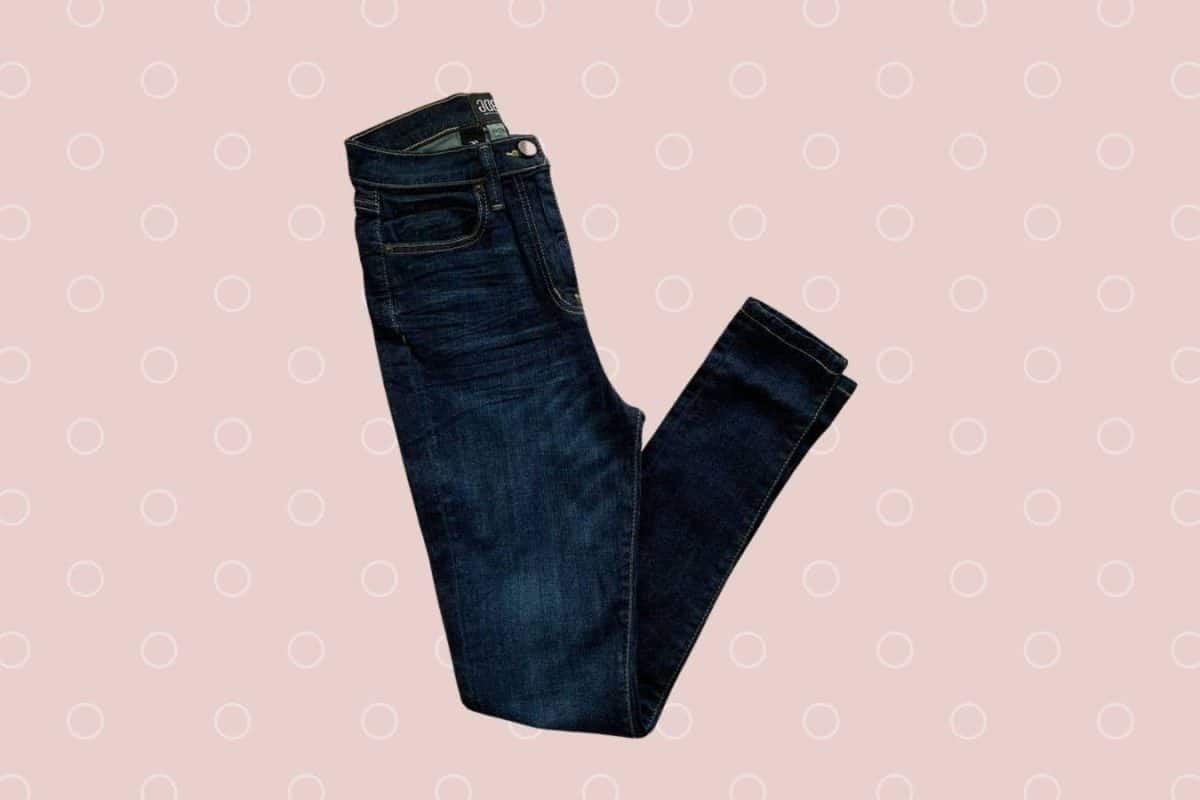 Dark blue fitted denim jeans placed on a pink background
